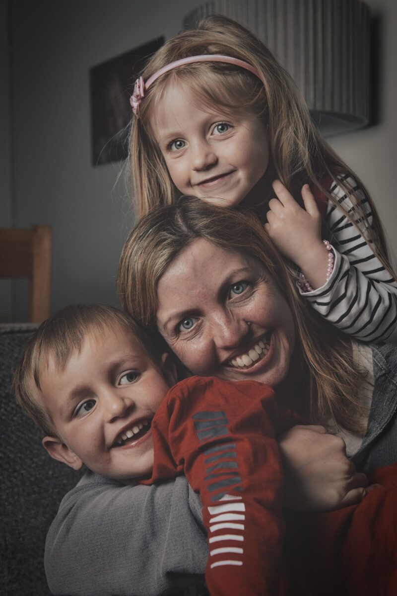 Fun picture of woman hugging a boy and girl smiling and having fun