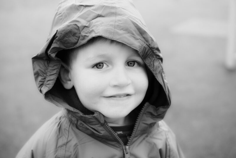 Young boy in a raincoat smiling to camera