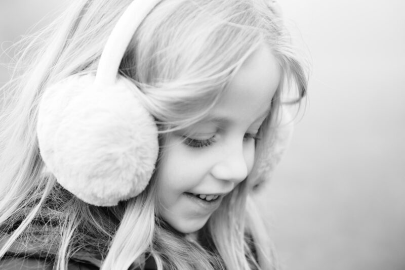 Young girl in ear muffs smiling and looking away from camera